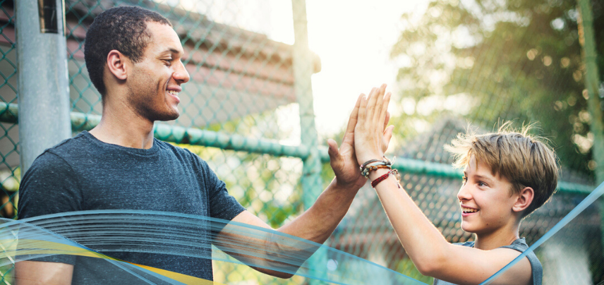 Image of male coach and young boy doing high 5